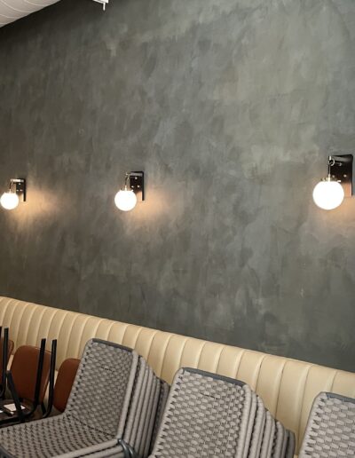 A row of chairs in a restaurant with a concrete wall.