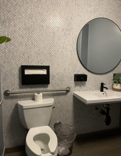 A bathroom with a toilet, sink and mirror.