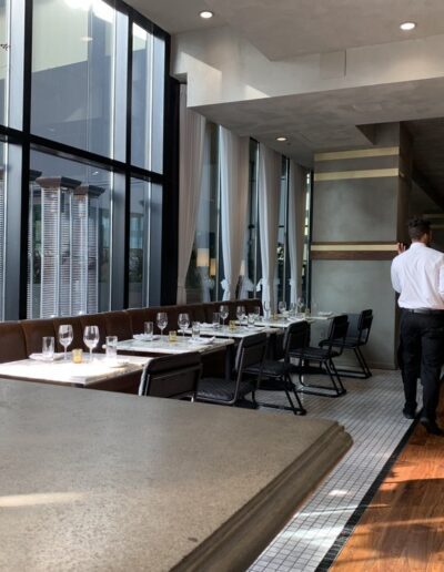 Two men walking through a restaurant with large windows.